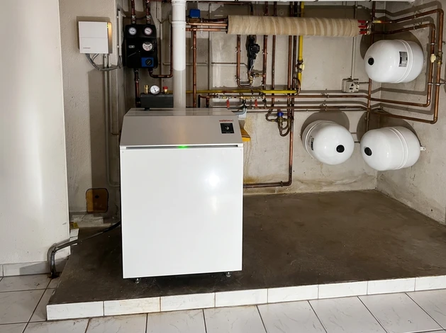 Radiateur blanc installé sur mur en briques peintes, sol carrelé intérieur